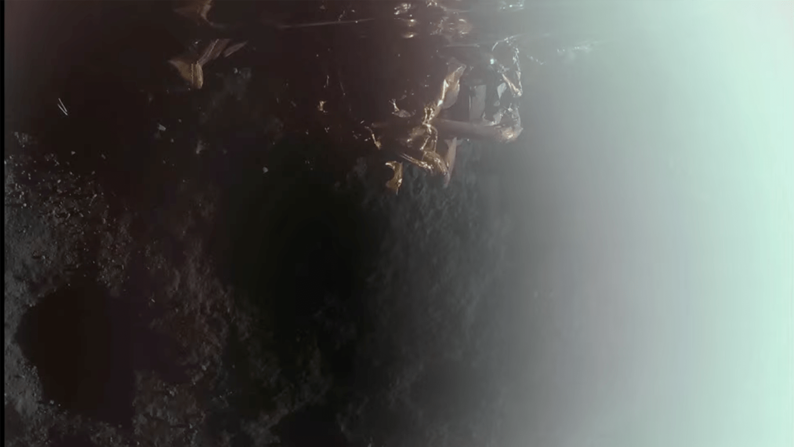Lunar surface with a robotic lander and debris, surrounded by shadows and light glare.