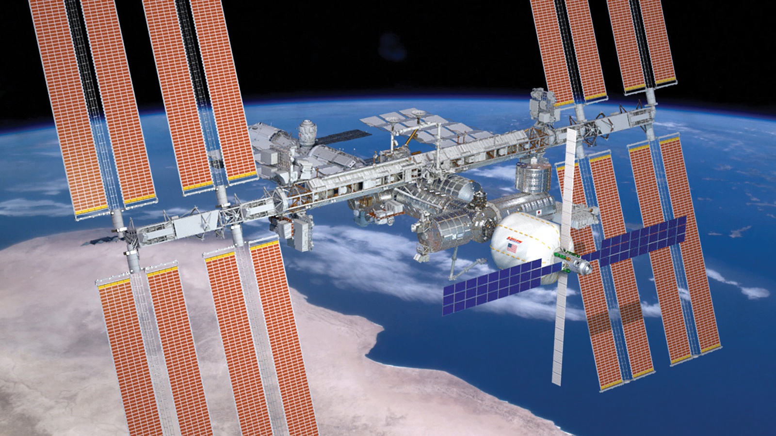 The International Space Station orbits Earth, displaying its extended solar panels and modules against a backdrop of the planet's surface and blue atmosphere.