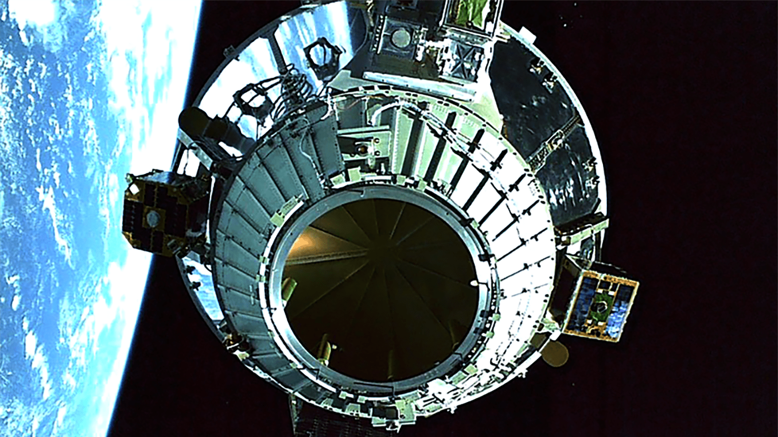 A close-up view of a spacecraft orbiting Earth with the blue and white planet visible in the background against the blackness of space.