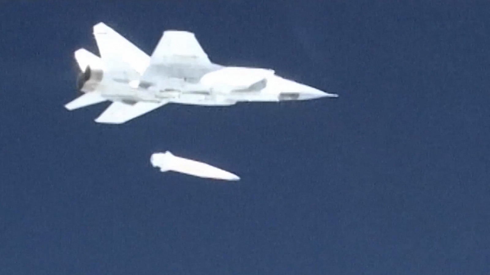 Jet flying through the sky releases a missile mid-air.