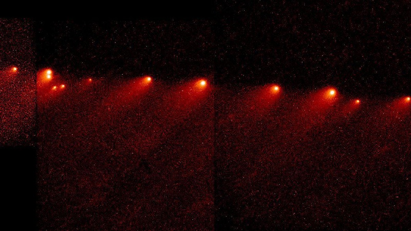 A series of bright red-orange objects against a dark background, resembling a comet or multiple meteors streaking across the sky.