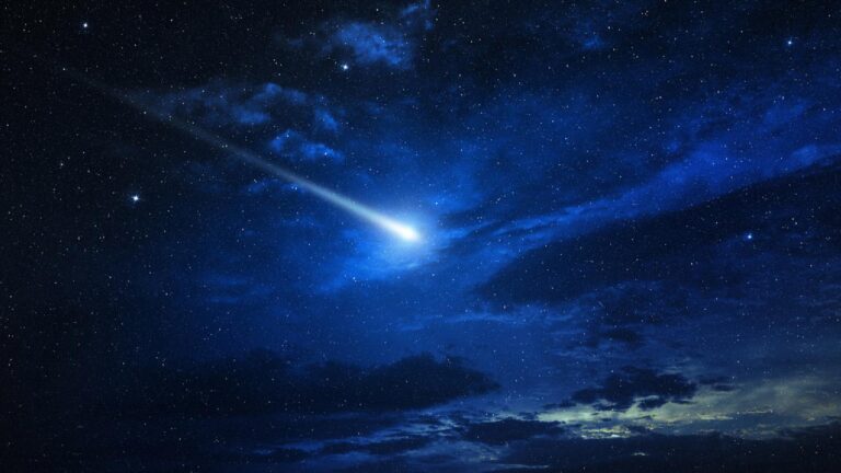 May 2018 AIAA Bulletin A bright meteor streaks across a star-filled night sky, illuminating the surrounding clouds with a vivid blue glow.