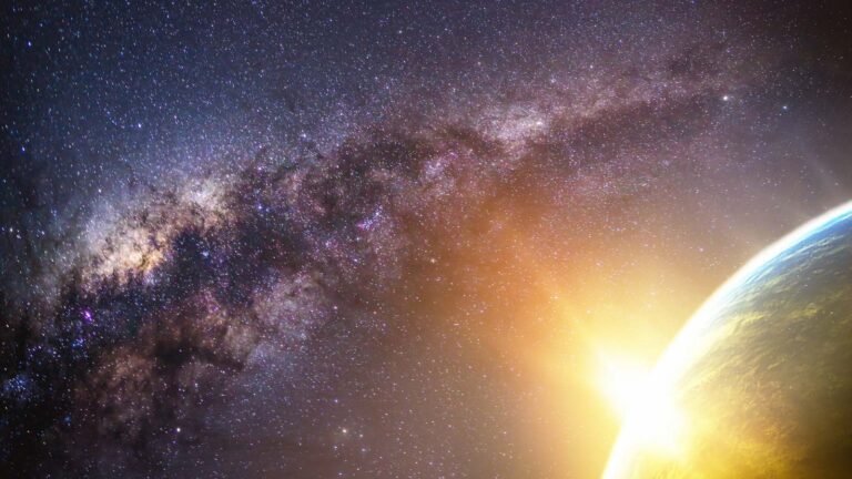 A view of the Milky Way galaxy with numerous stars and cosmic dust, seen above a brightly lit horizon of a planet on the right.