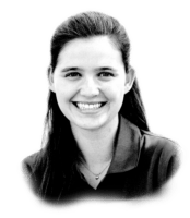 Black and white photo of a smiling woman with long, dark hair, wearing a collared shirt. She is looking directly at the camera.