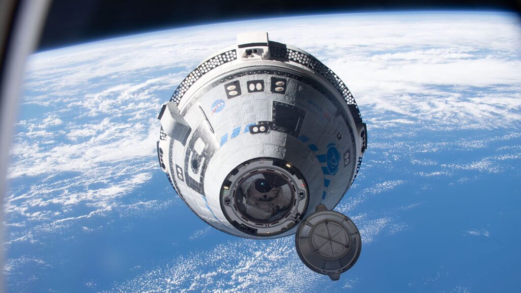 A spacecraft orbits above Earth, with the planet's blue surface and white clouds visible below. An open hatch is noted on the spacecraft's exterior.