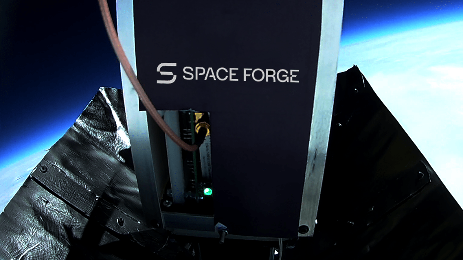 Close-up of a Space Forge device in space, with the Earth and blackness of space in the background. The device has the Space Forge logo on its exterior.