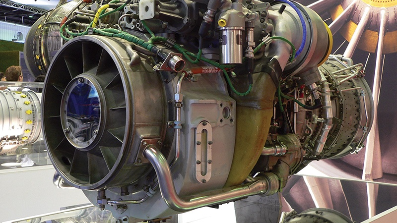 Detailed view of an exposed jet engine showing internal components and wiring, displayed at a trade show.