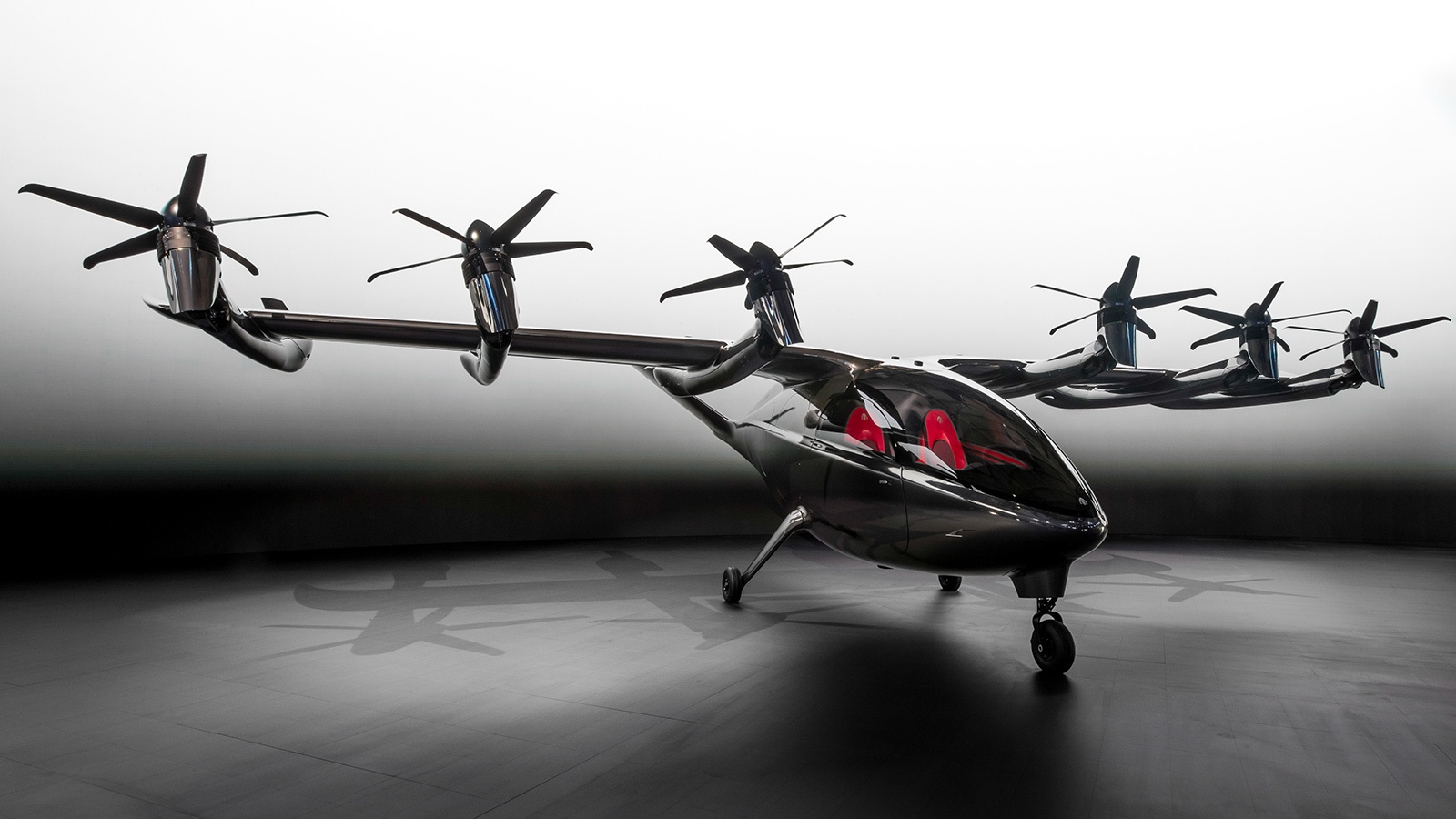 A sleek black vertical takeoff and landing (VTOL) aircraft with multiple rotors and red interior lighting is displayed in a minimalist setting.