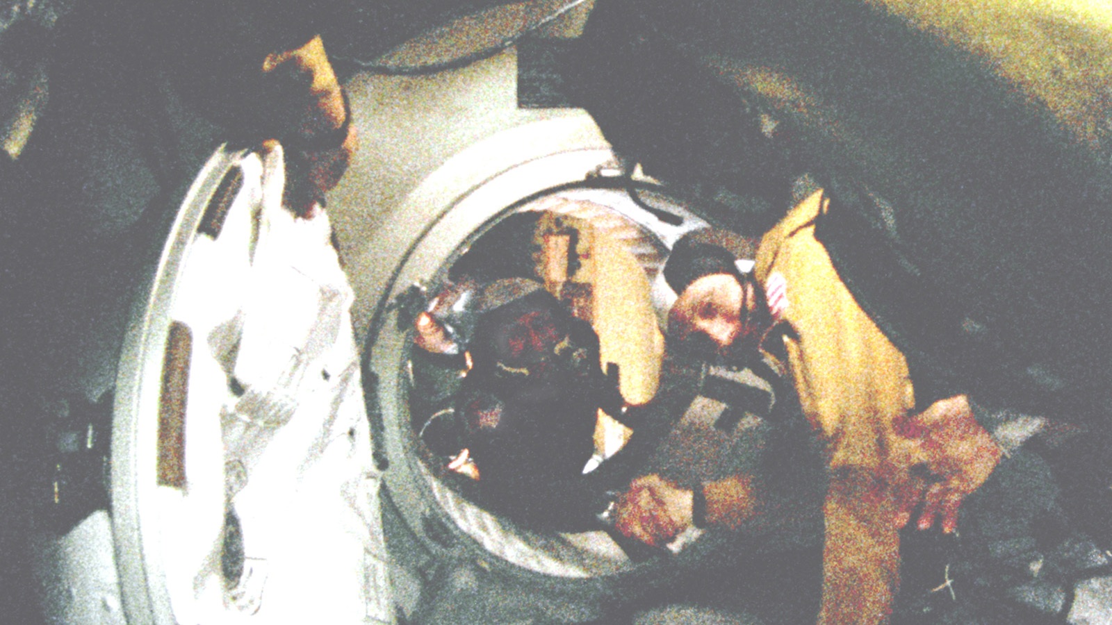 Astronauts exchange a handshake between two spacecrafts through an open hatch during a space mission.