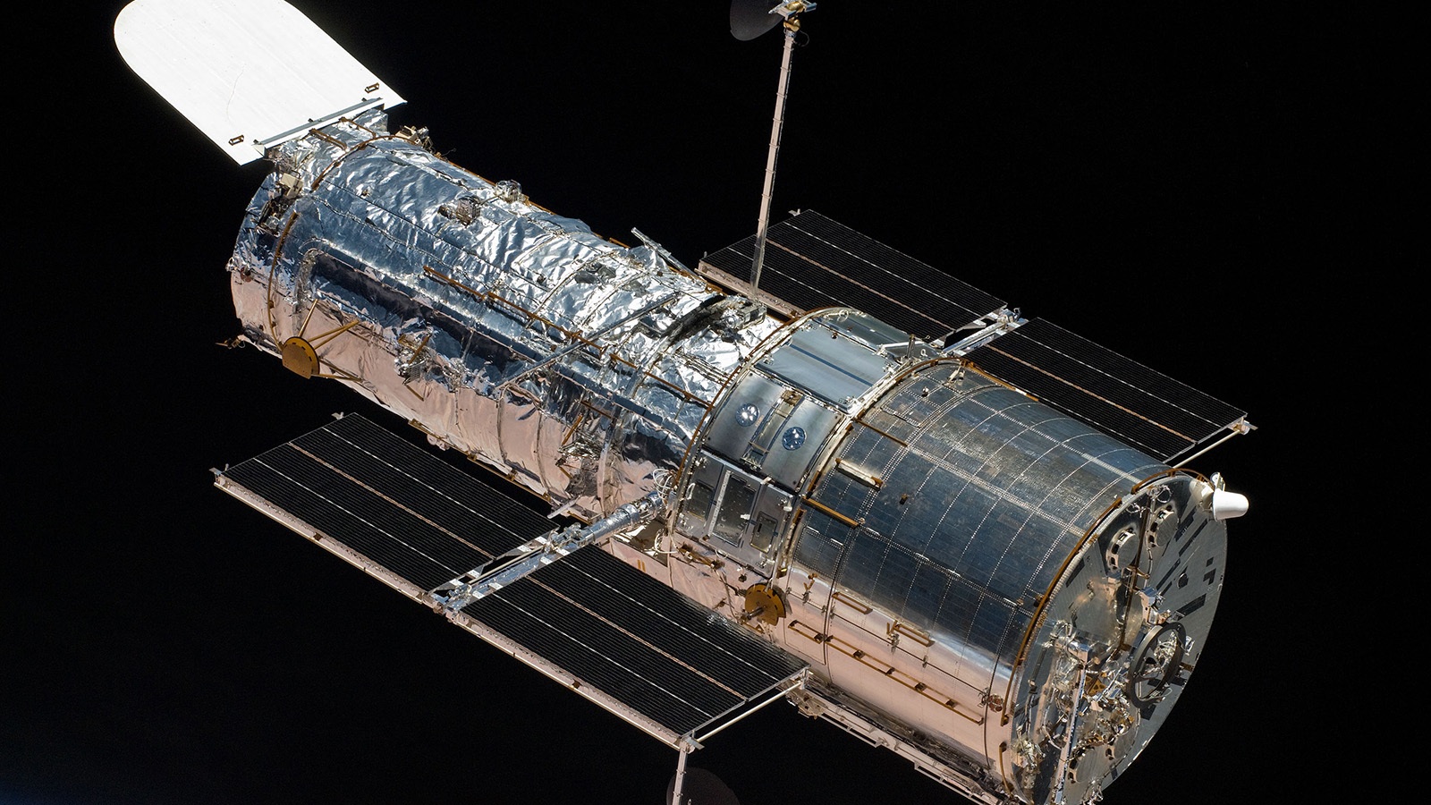 A detailed view of the Hubble Space Telescope floating in space with its solar panels extended and various instruments visible against a black background.